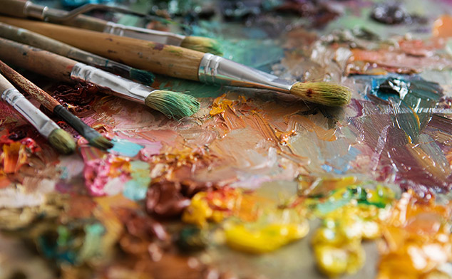 Used artist paint brushes laying on a colorful palate. 