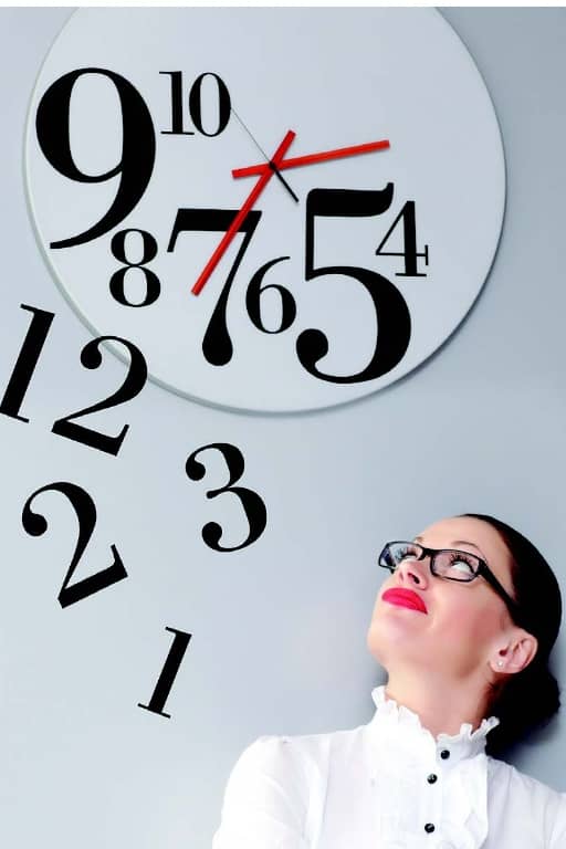 Photo of a woman looking up as the numbers fall off a clock.