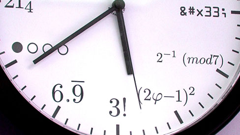 Close up on the face of a clock where math symbols are displayed instead of number.